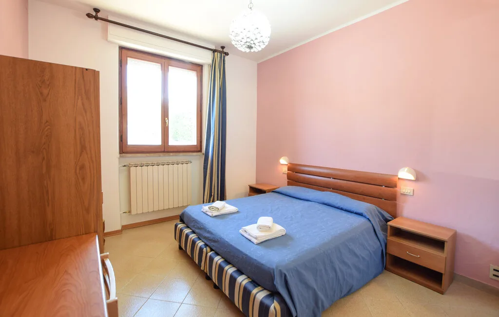 Un dormitorio con una cama cubierta de azul junto a una ventana.