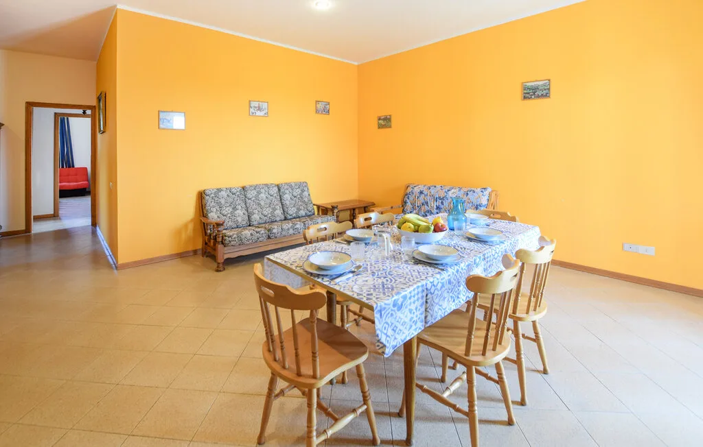 Comedor con una mesa puesta y asientos junto a paredes de color amarillo intenso.