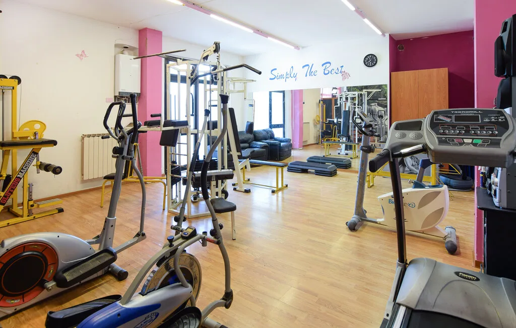 Un gimnasio interior con máquinas de ejercicio y una pared con espejo.
