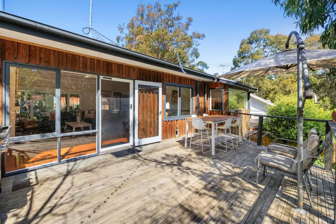 A wooden deck with outdoor seating beside a house.