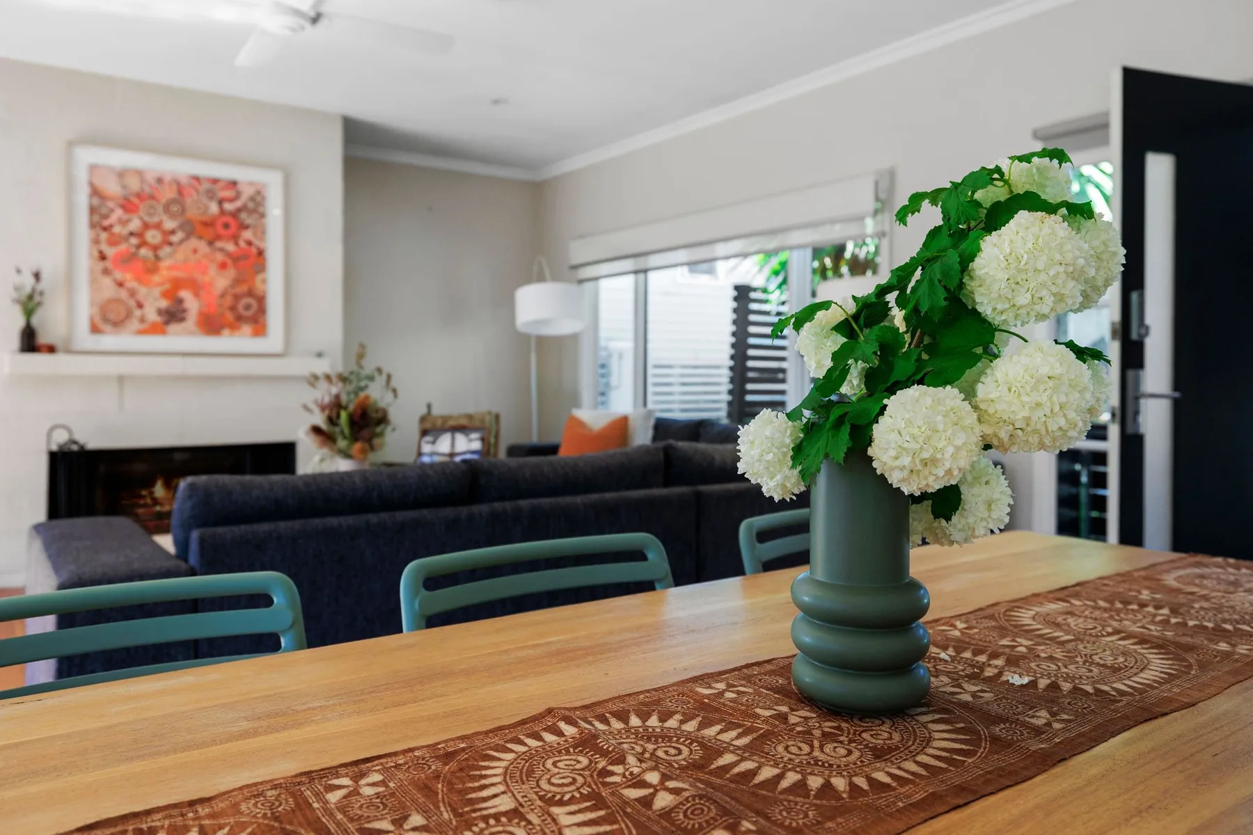 A living room and dining area with a wooden table and flower arrangement.
