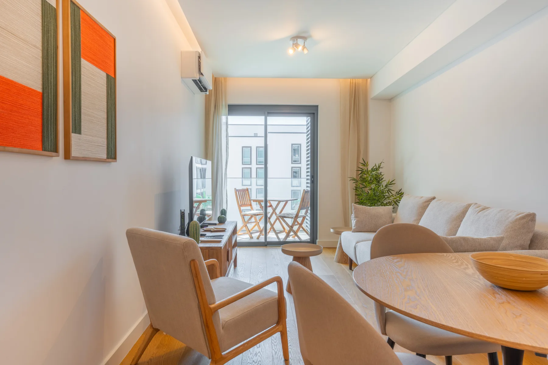 Una luminosa sala de estar y comedor con asientos, una mesa y puertas al balcón.