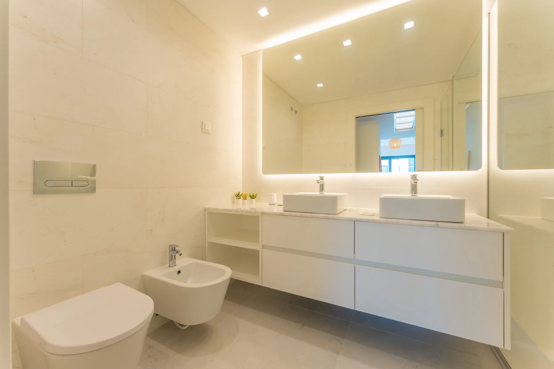 Un baño luminoso con un lavabo doble y un bidé.