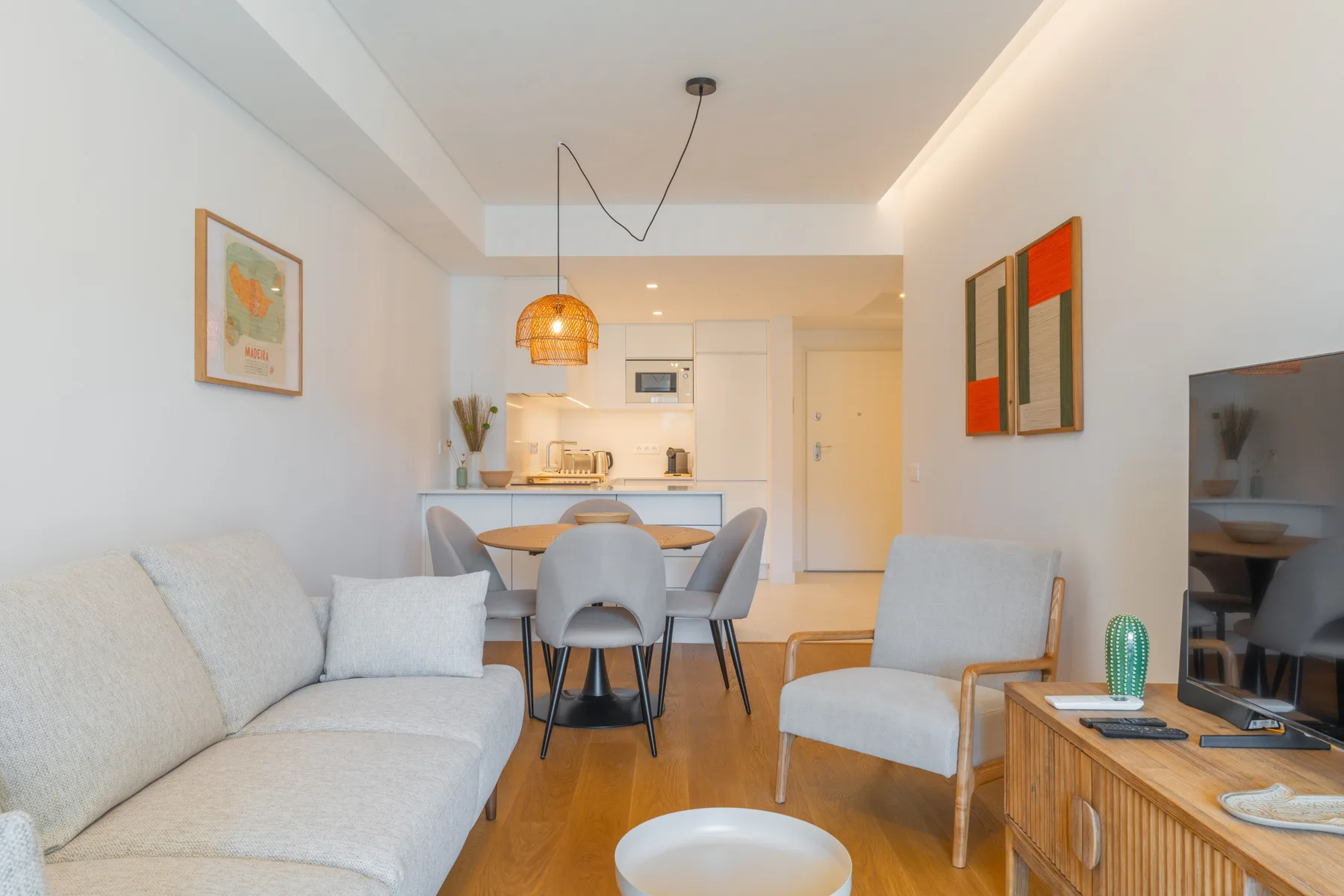 Una luminosa sala de estar y comedor con asientos, una mesa y la cocina al fondo.