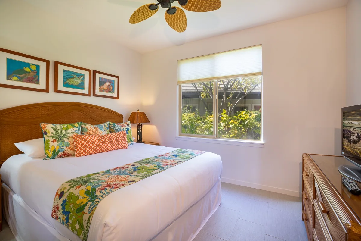 Un dormitorio con una cama bien hecha y una ventana con vistas a la vegetación.