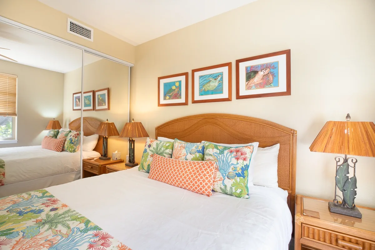 Un dormitorio con una cama, almohadas coloridas y cuadros en la pared.