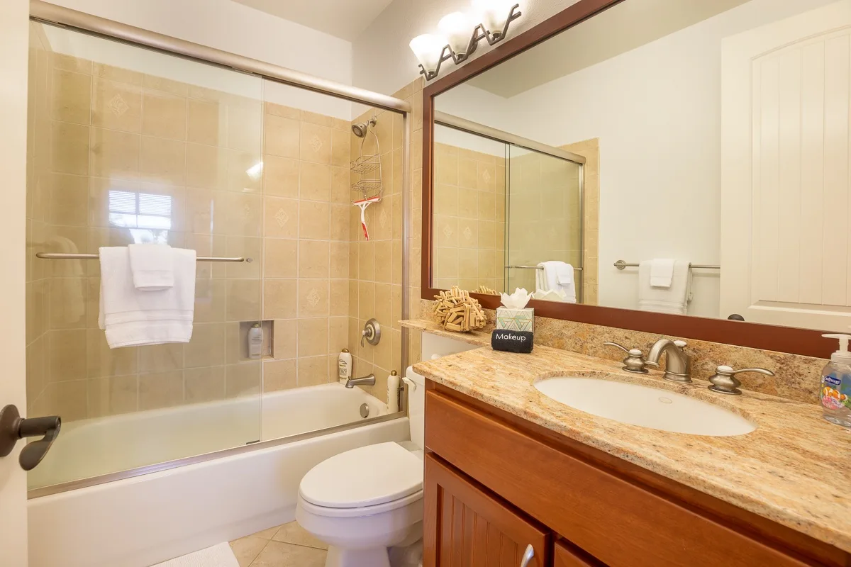 Un baño con ducha de azulejos, inodoro y lavabo con mueble.