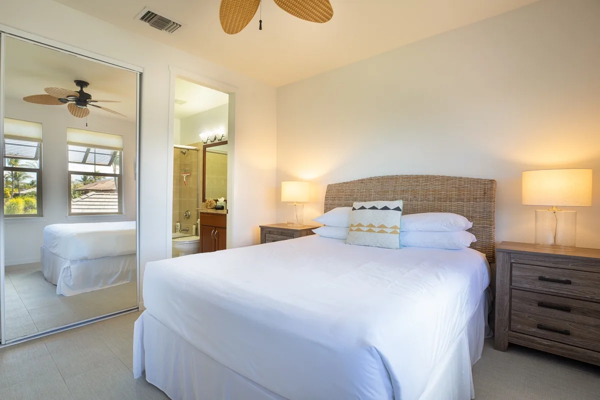 Un dormitorio luminoso con una cama bien tendida y puertas de armario espejadas.