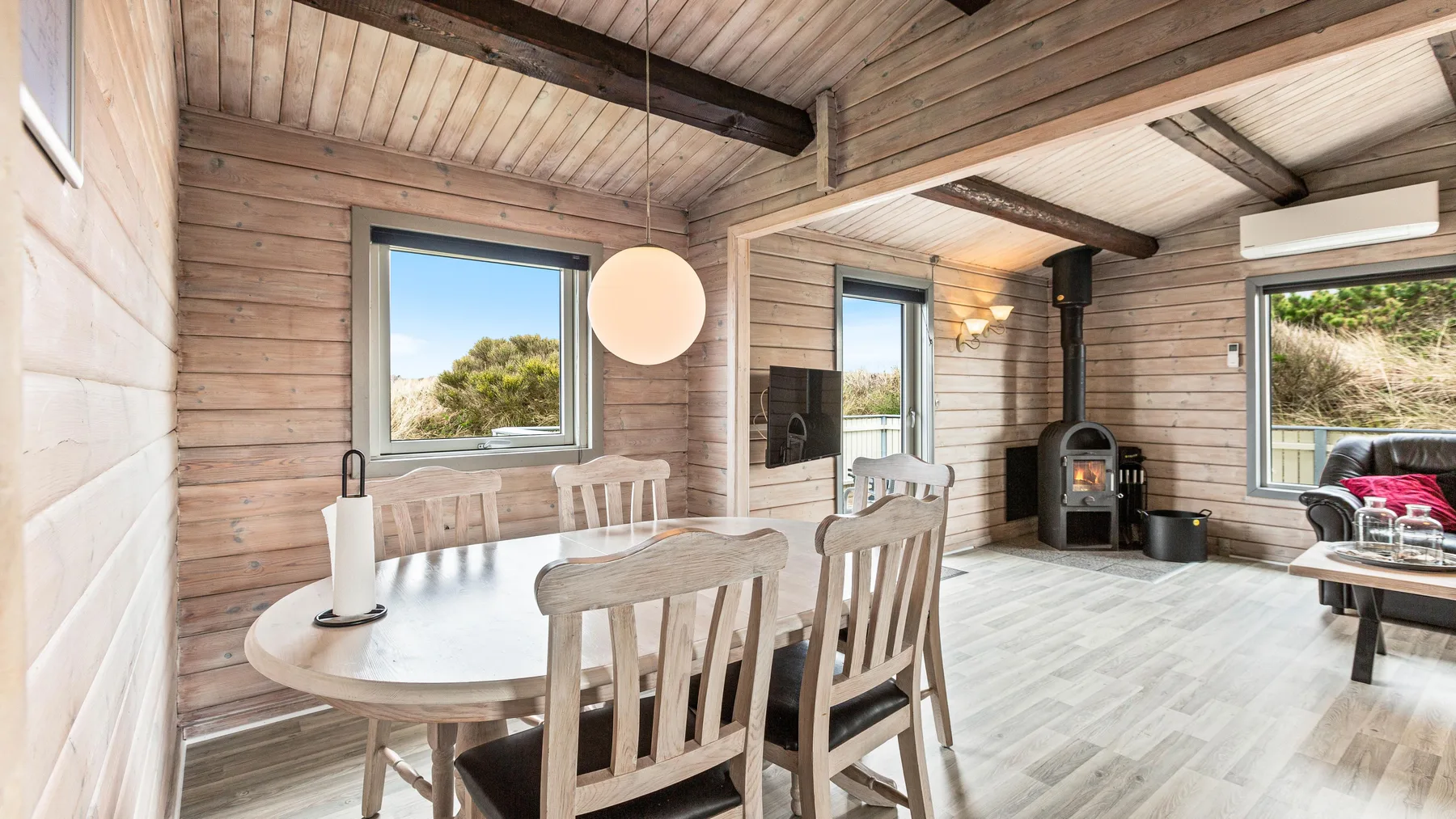 Un luminoso comedor de madera con mesa, sillas y una estufa.