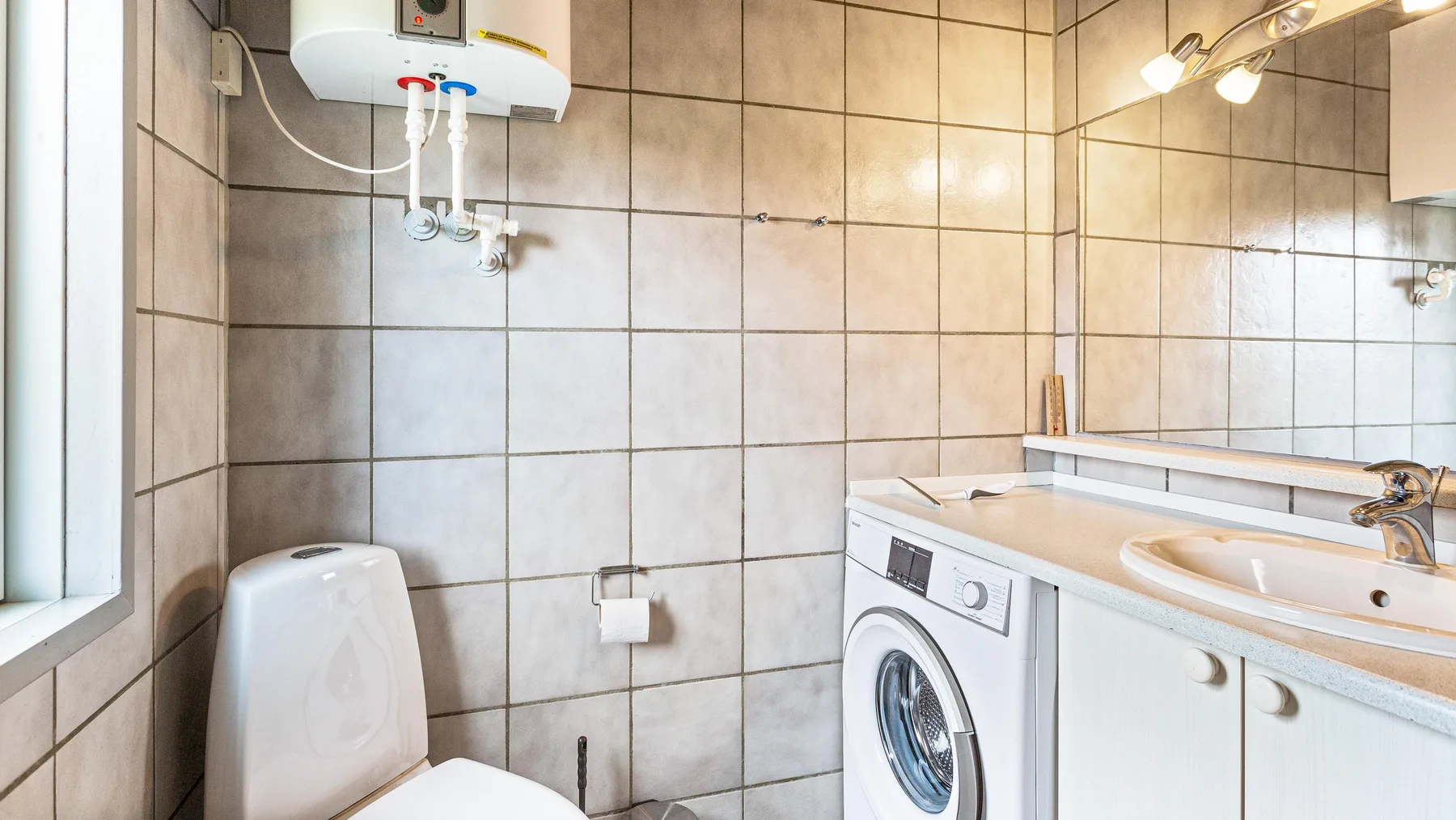 Un baño alicatado con inodoro, lavadora y lavabo.