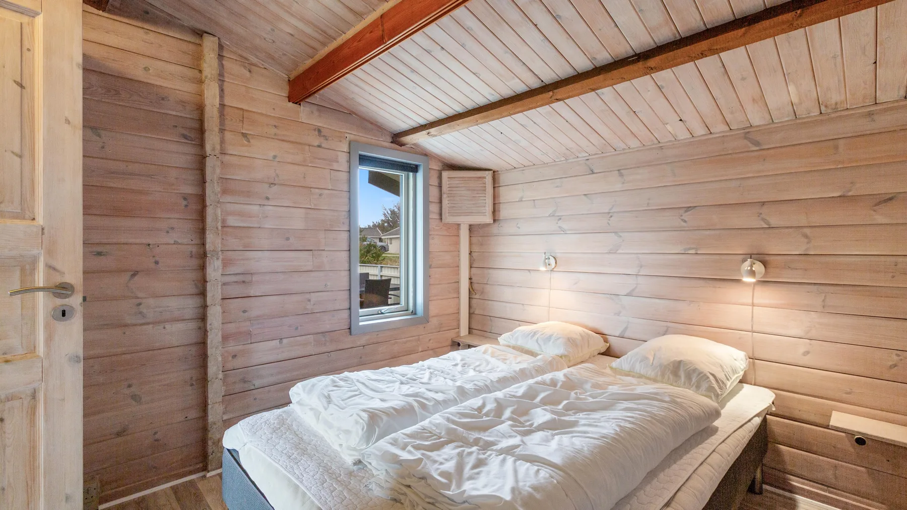 Un dormitorio con una cama bajo un techo inclinado revestido de madera.
