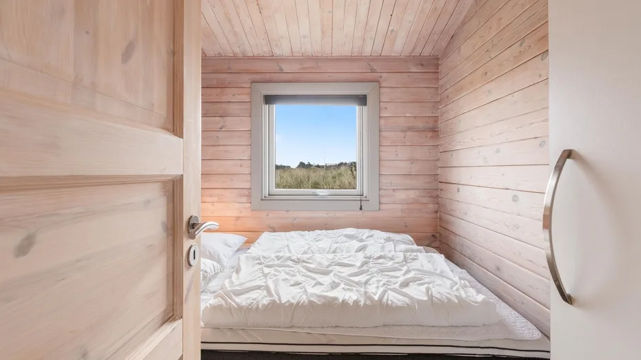 Un dormitorio compacto con una cama debajo de una ventana.