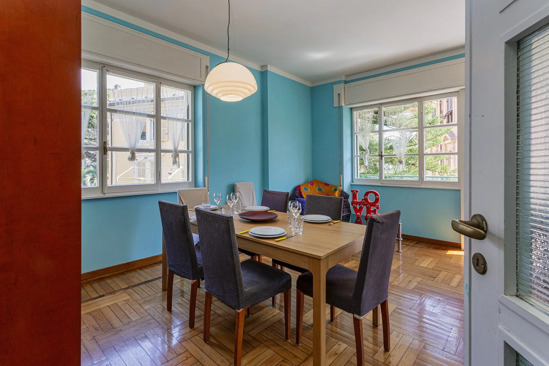 A dining area with a wooden table and seating beside large windows.