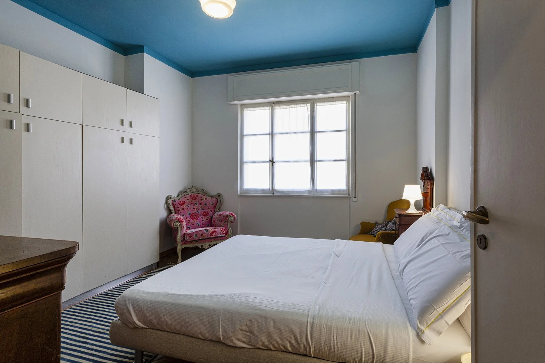 Un dormitorio con una cama, armarios empotrados y una ventana.