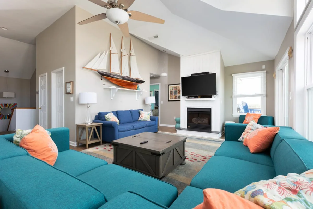 A bright living room with teal seating, a coffee table, and a fireplace.