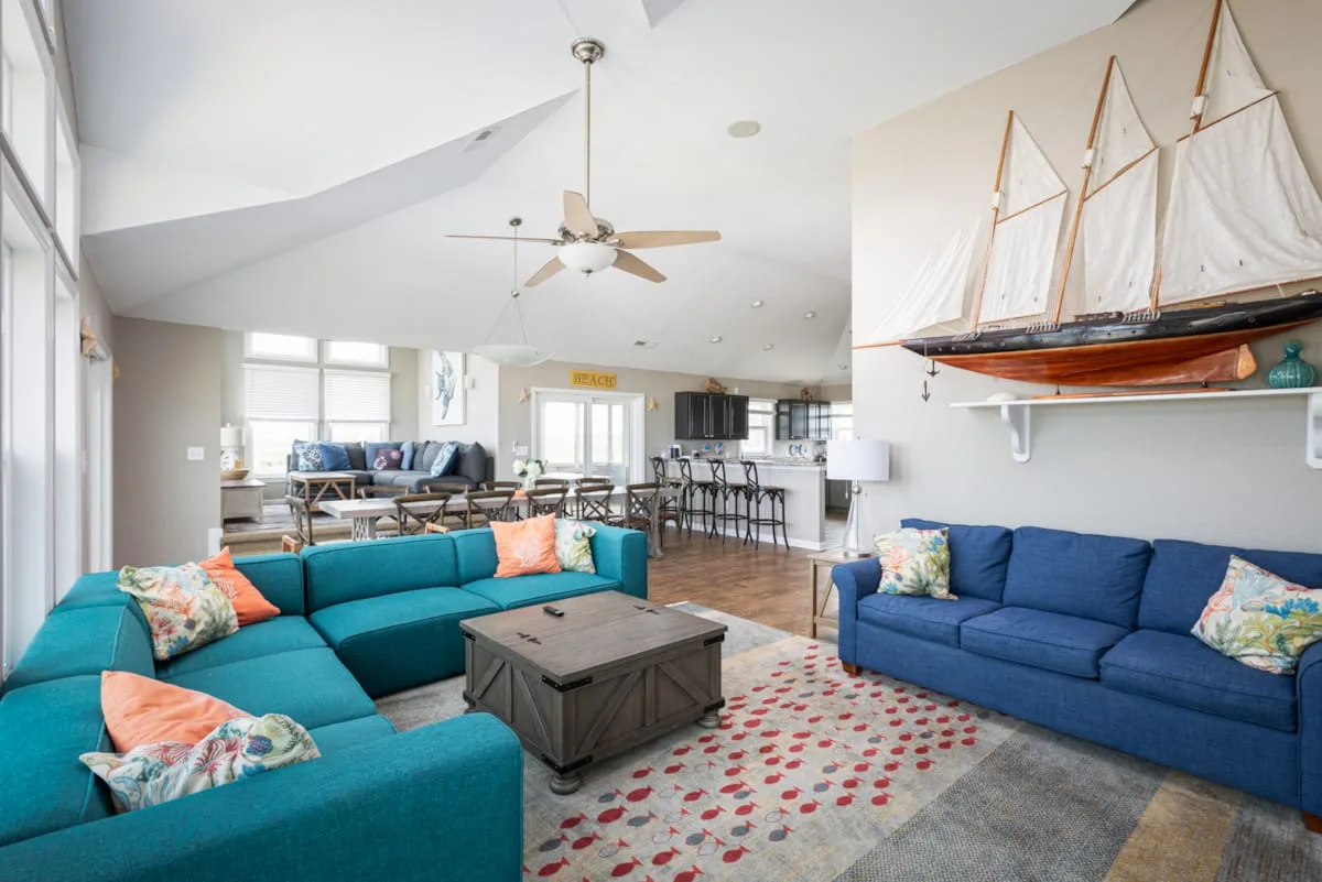 A bright living room with colorful seating and a dining area behind it.
