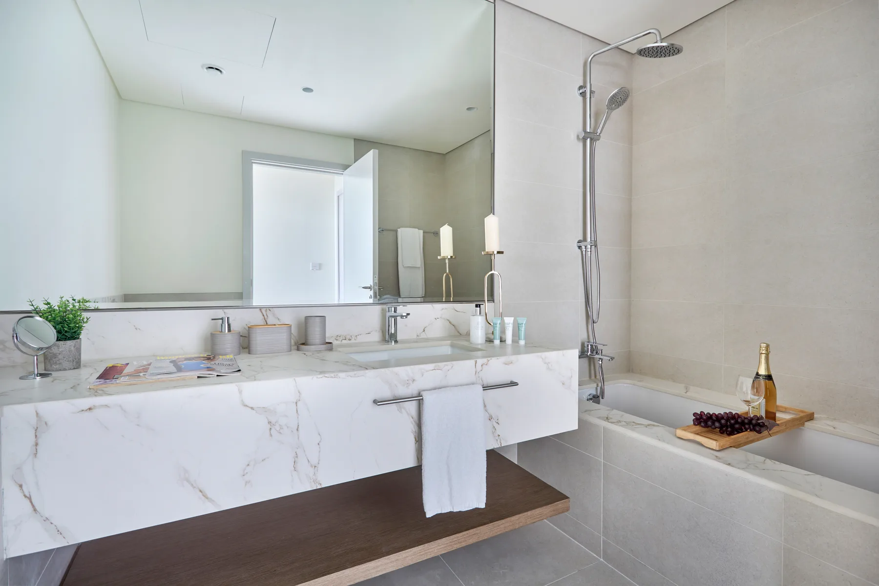 A bright bathroom with a wide vanity, mirror, and bathtub with a shower.