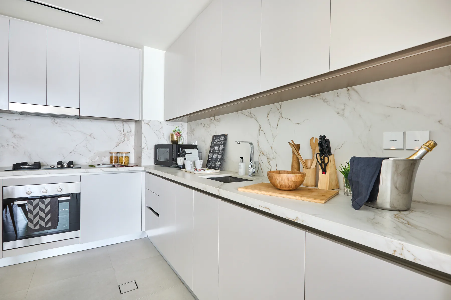 A bright modern kitchen with white cabinets and a long countertop.
