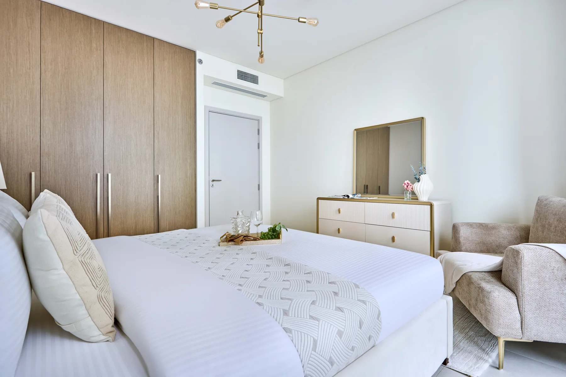 A bright bedroom with a neatly made bed and a small seating area.