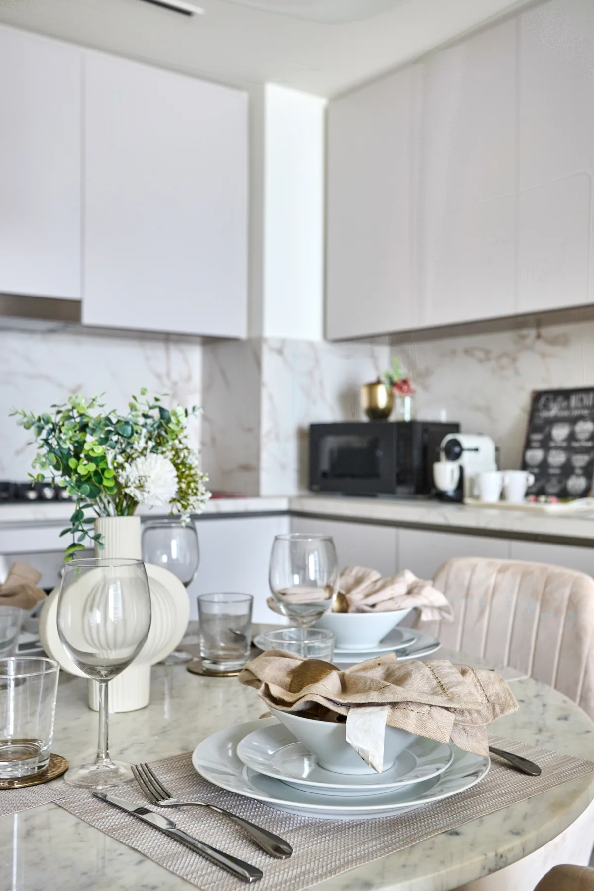 A bright kitchen dining area with a table set with plates and glasses.