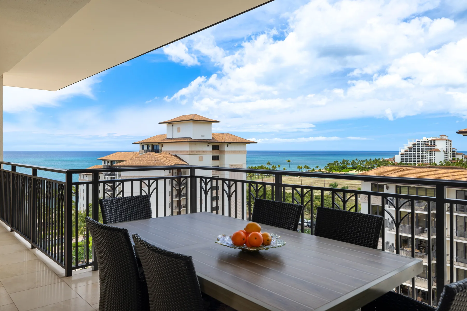A balcony dining area overlooks the ocean and nearby buildings.