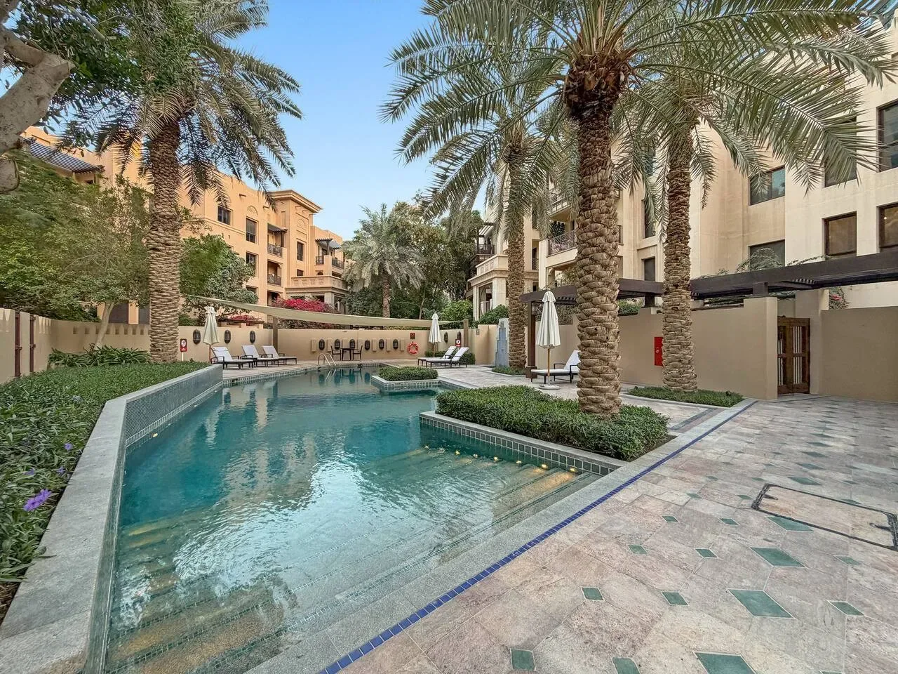 Una piscina está rodeada de palmeras y edificios.