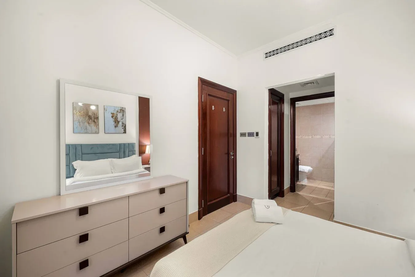 Un dormitorio con cama, cómoda y una puerta abierta al baño.