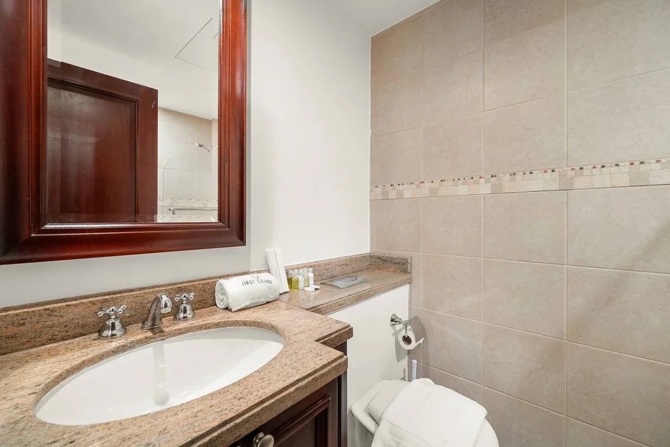 Un baño con lavabo, espejo y paredes de azulejos.