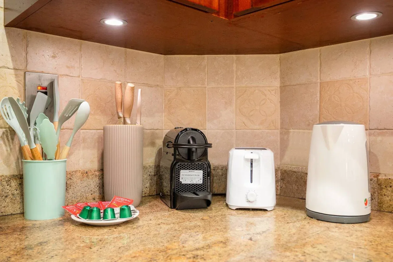 Una encimera de cocina con pequeños electrodomésticos y utensilios de cocina.