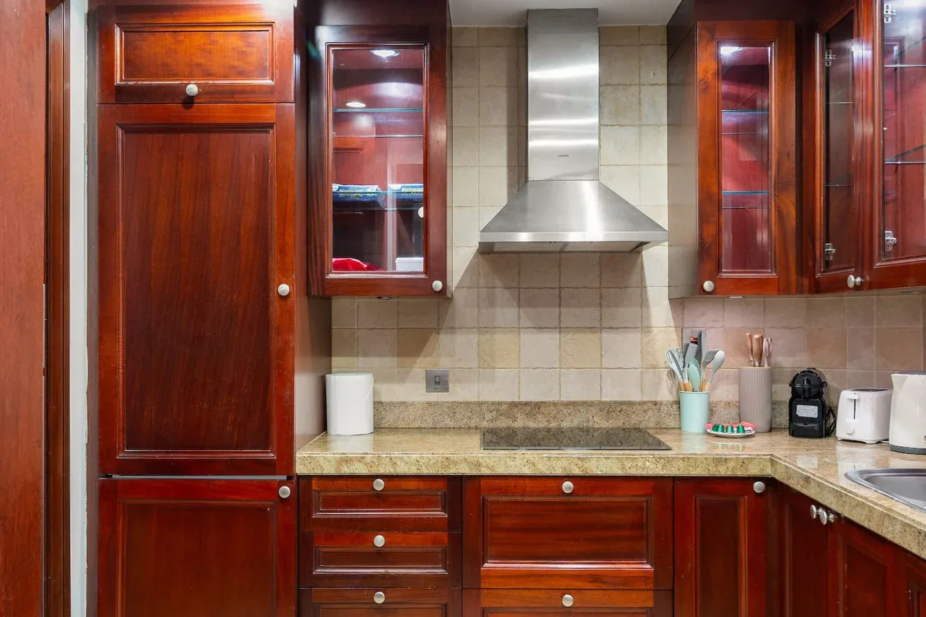 Una cocina con armarios de madera, un salpicadero de azulejos y una campana extractora de acero inoxidable.
