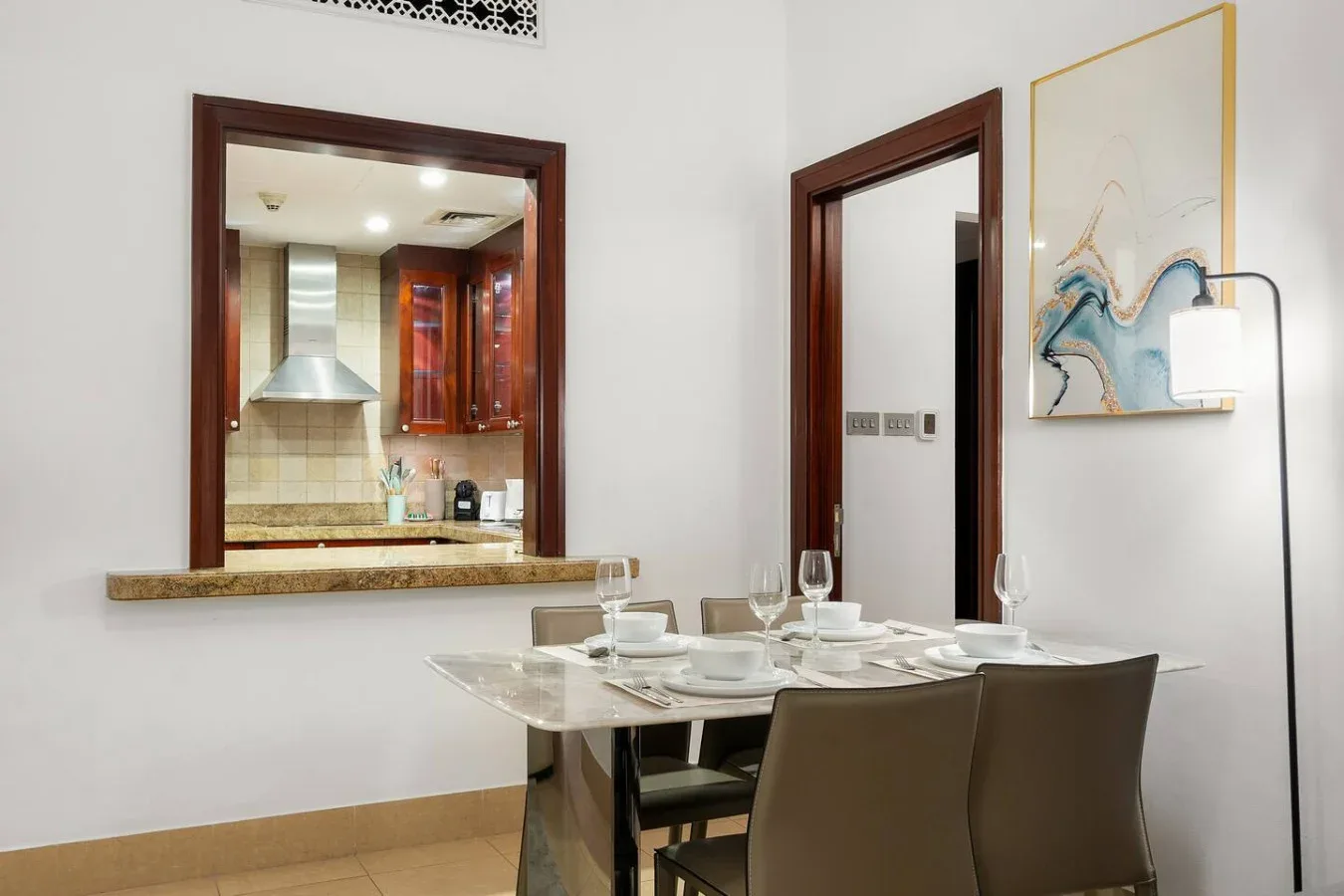 Comedor con la mesa puesta junto a una abertura hacia la cocina.