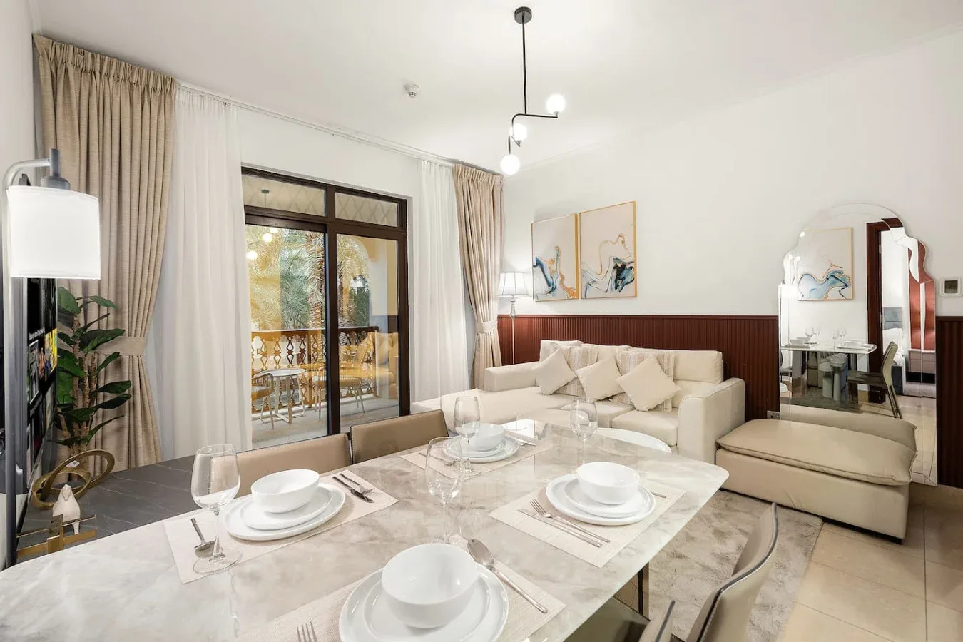 Una luminosa sala de estar y comedor con asientos junto a altas ventanas con cortinas.