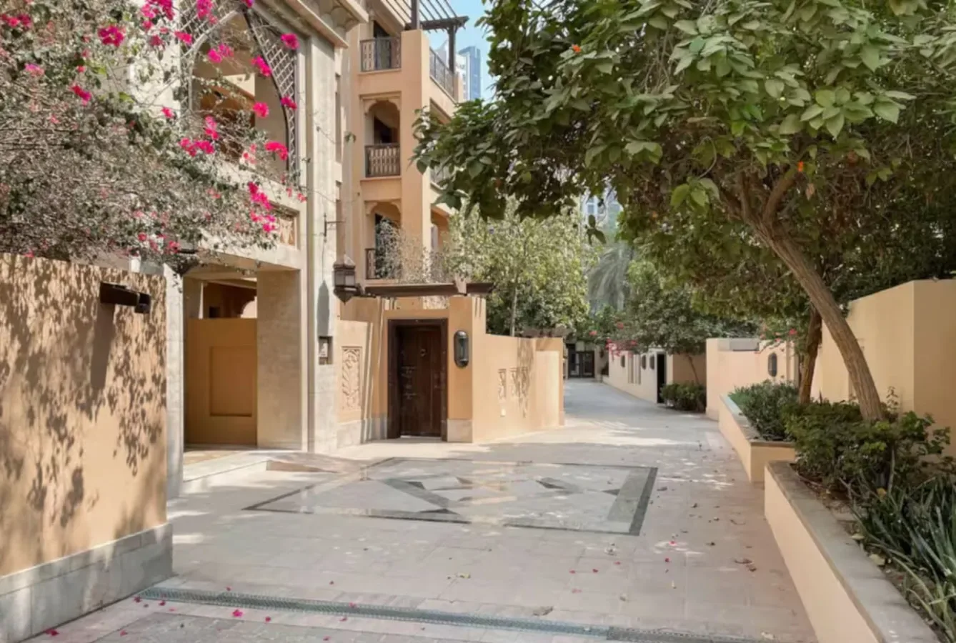 Un camino residencial pavimentado pasa entre edificios de apartamentos y árboles frondosos.