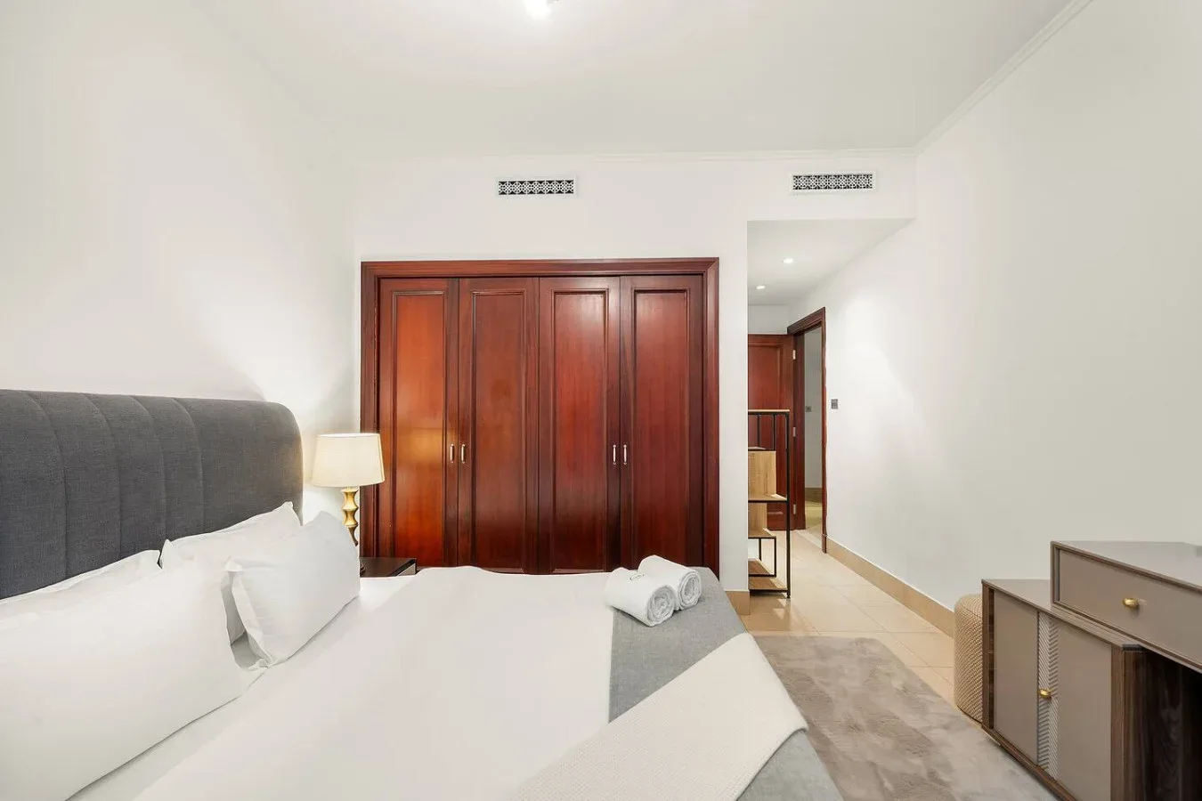 Dormitorio con una cama, armarios de madera y una puerta al pasillo.