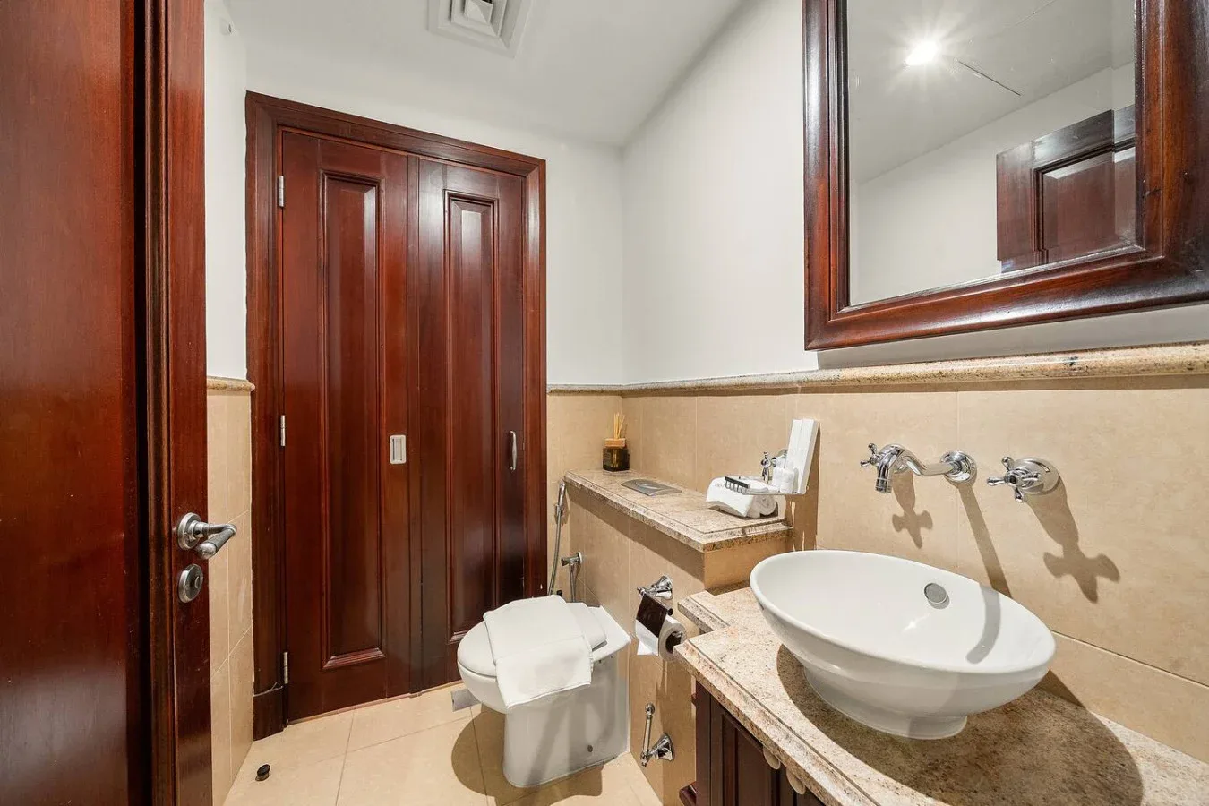 Un baño con lavabo, inodoro y puertas de paneles de madera.