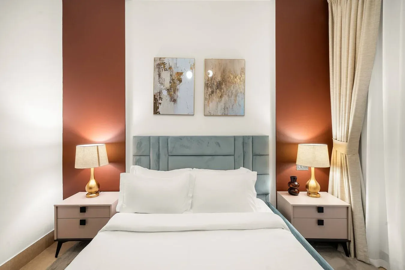 Un dormitorio con una cama, mesitas de noche a juego y arte abstracto en la pared.