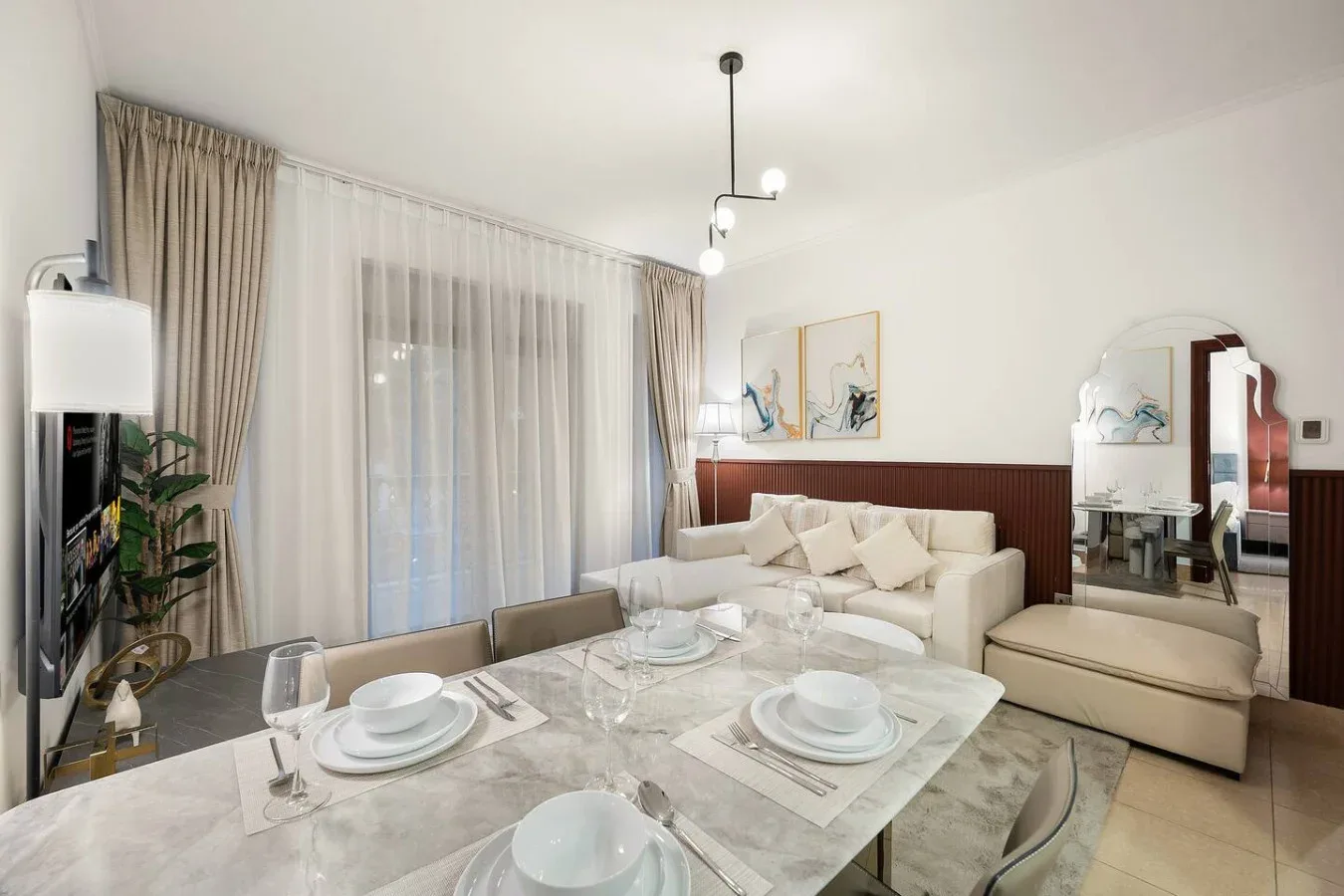 Una zona de estar y comedor con asientos color crema junto a una mesa puesta.