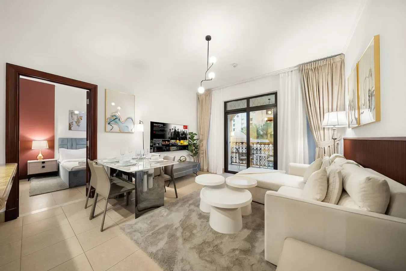 Sala de estar y comedor diáfanos con sofá, mesa de comedor y puertas al balcón.