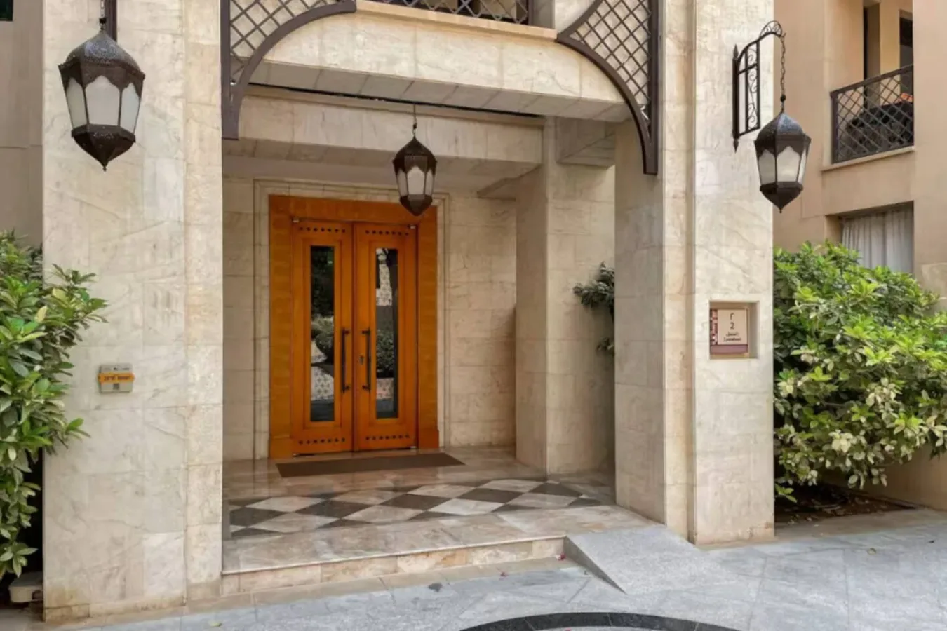 Una entrada retranqueada con puertas dobles de madera y pavimento de piedra.