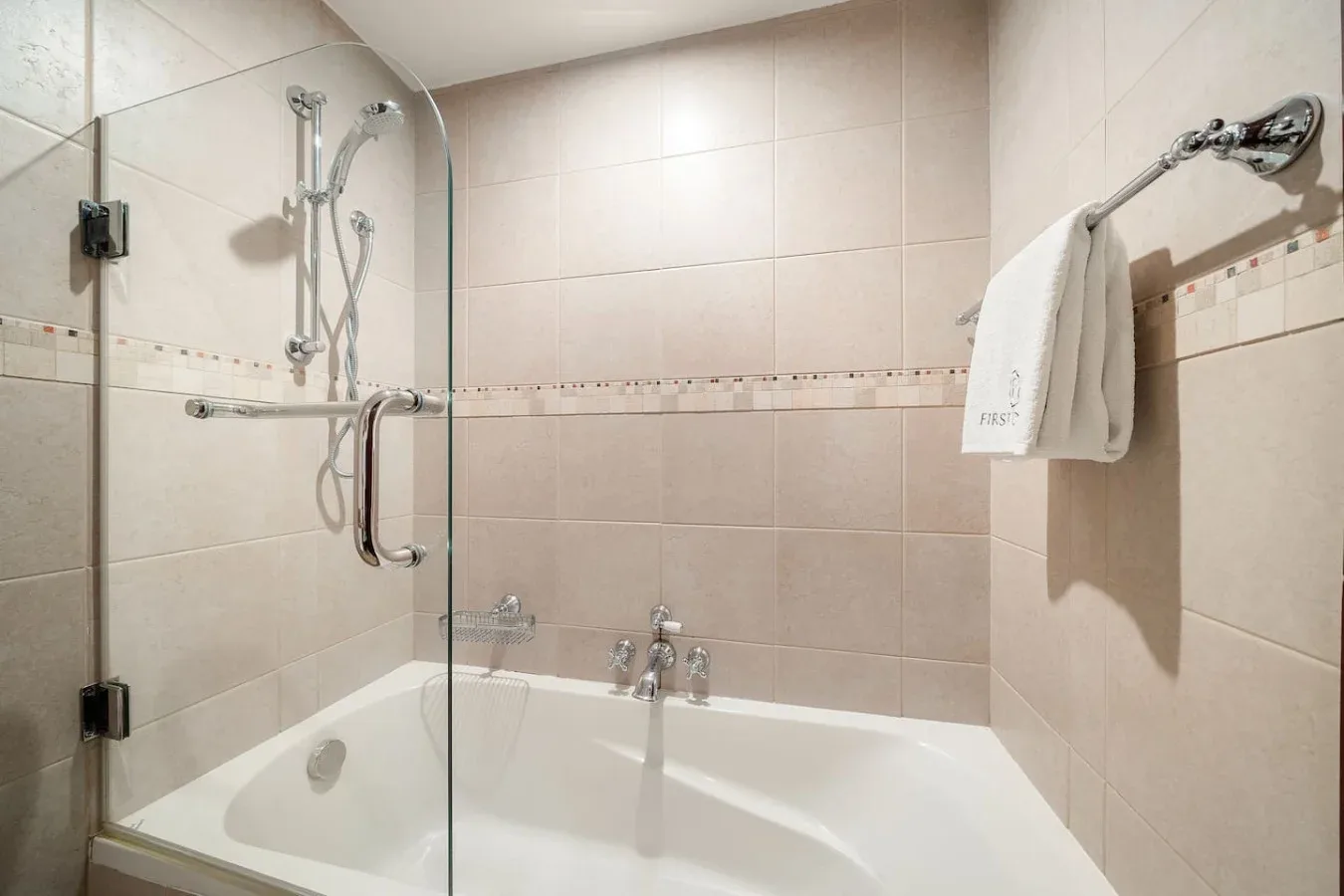 Un baño alicatado con bañera y mampara de ducha de vidrio.