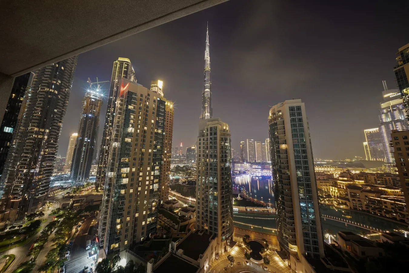 Un horizonte urbano nocturno con edificios altos iluminados y una torre esbelta en el centro.