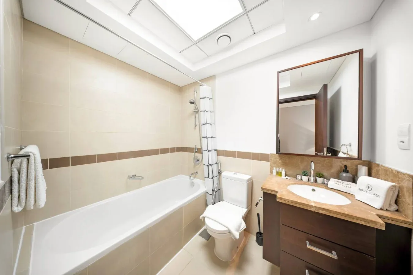 Un baño luminoso con bañera, inodoro y lavabo con mueble.
