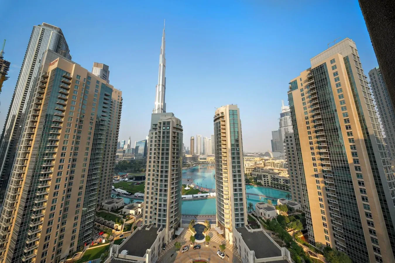 Vista elevada del horizonte urbano, con edificios altos alrededor de una piscina turquesa.