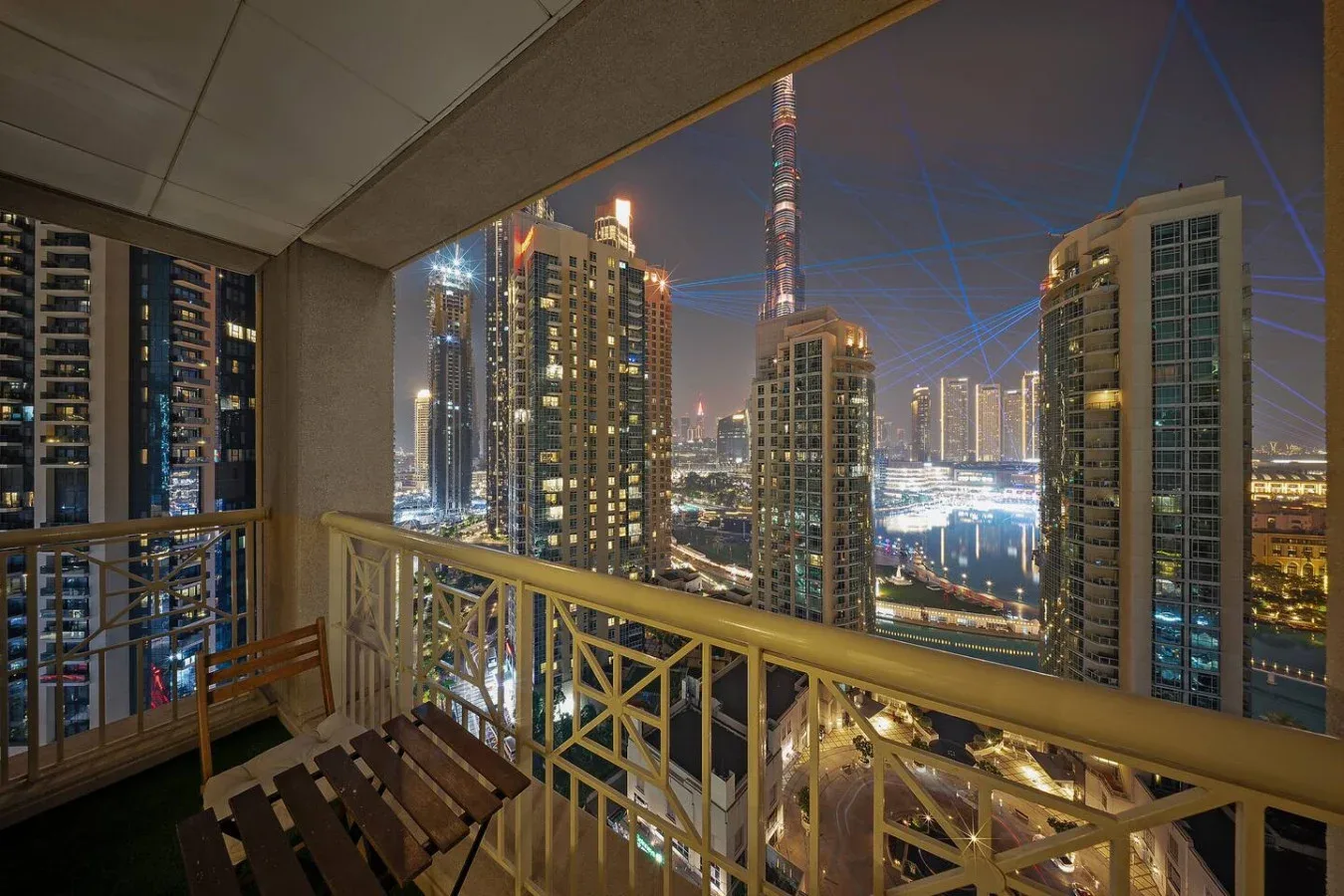 Un balcón da a edificios altos iluminados y al horizonte de la ciudad de noche.