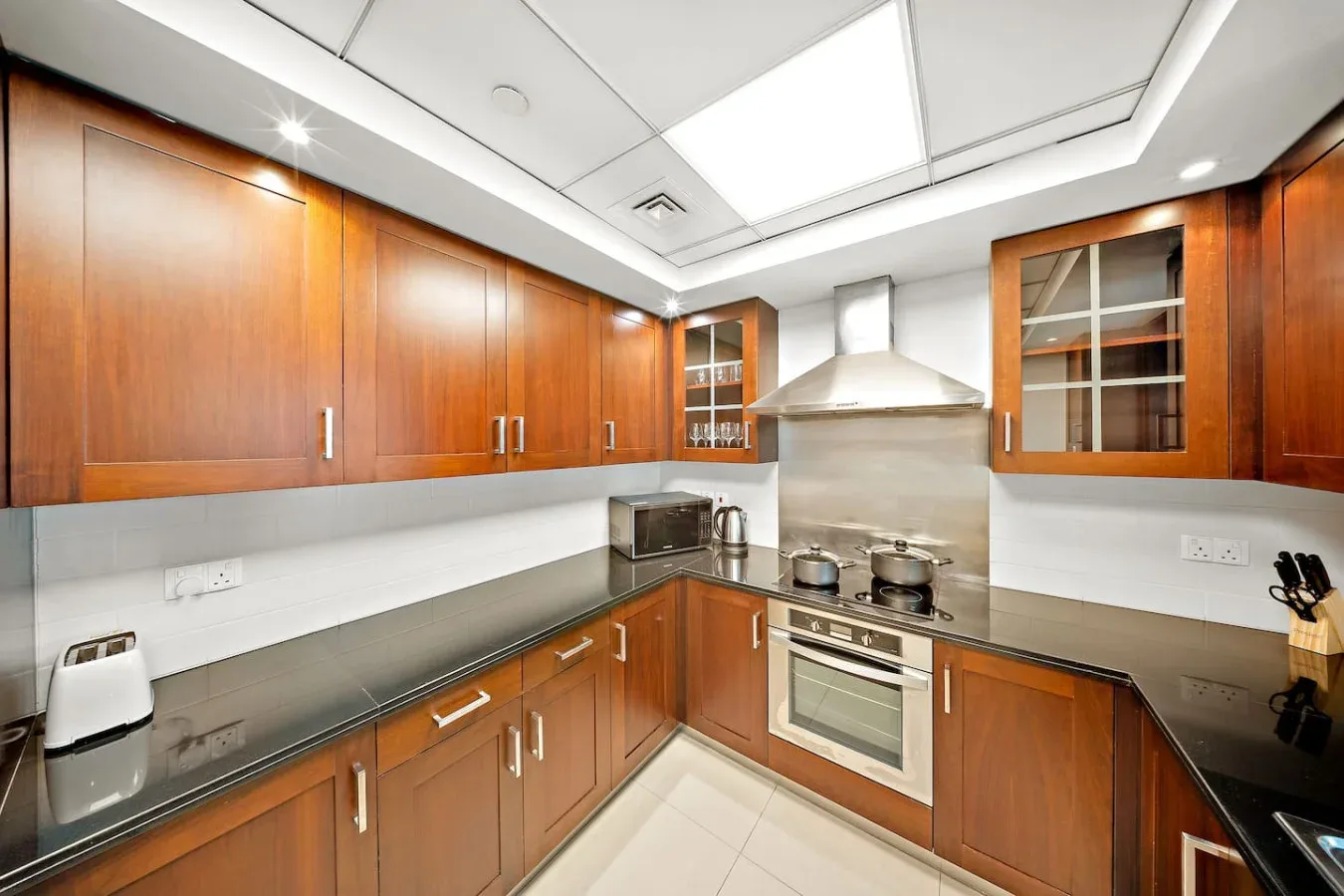 Una cocina moderna con gabinetes de madera, una placa de cocina y un horno integrado.