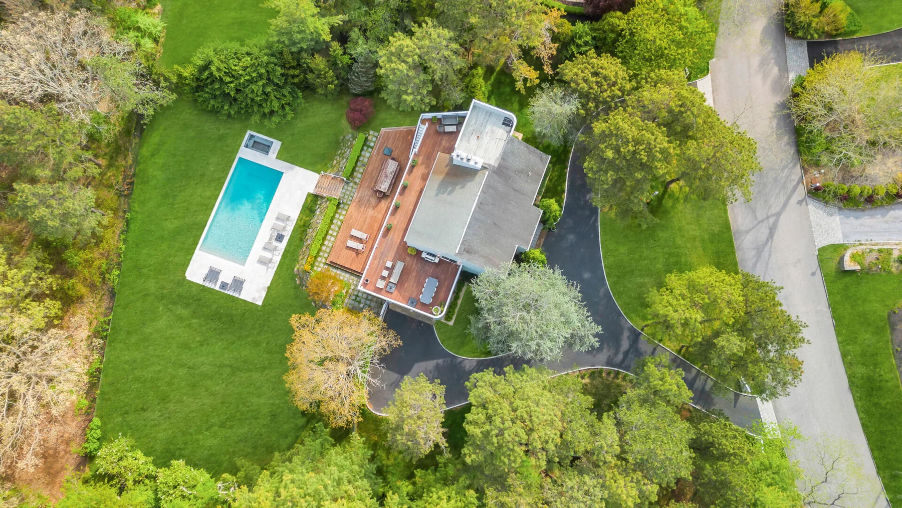 Aerial view of a house, swimming pool, and surrounding green grounds.