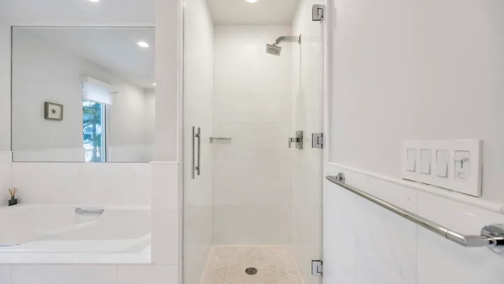 A bright bathroom with a glass shower and a sink beneath a mirror.