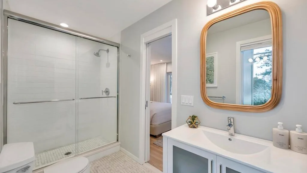 A bright bathroom with a glass shower and a wide vanity.