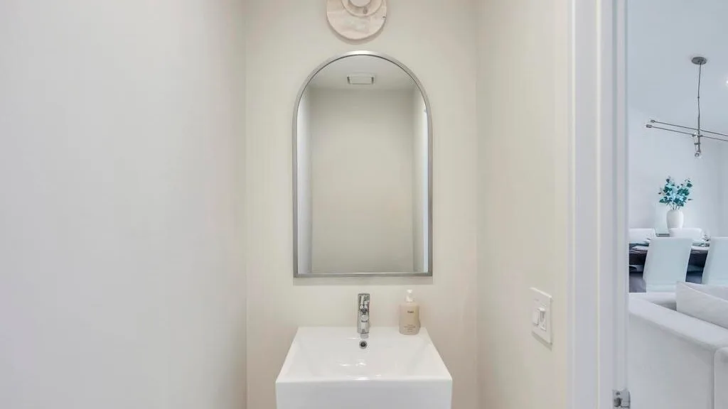 A bathroom vanity with a sink and arched mirror.