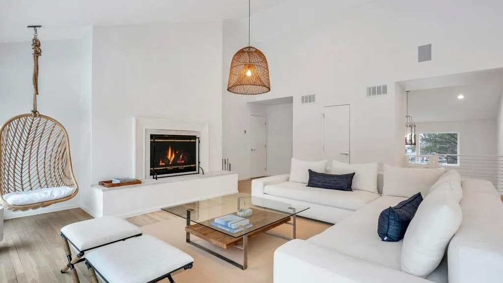 A bright living room with white seating and a glass coffee table.